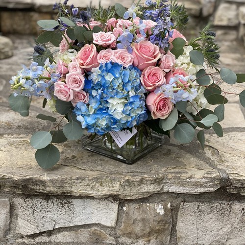Pink roses and blue hydrangeas with eucalyptus in a glass cube vase from floral design studio Raleigh