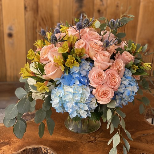 Blush roses with blue hydrangeas thistle and yellow alstroemeria from Raleigh flower studio