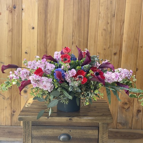 Pink stock red anemones and burgundy calla lilies in a dark vessel by flower studio Raleigh NC