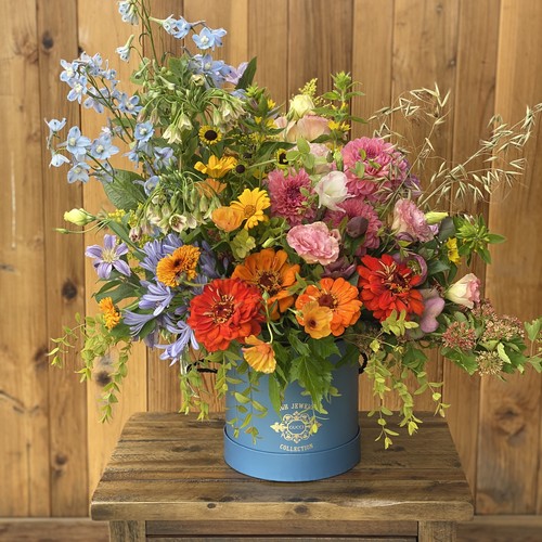 Colorful wildflower arrangement with zinnias and delphiniums in a blue hat box by floral design studio Raleigh